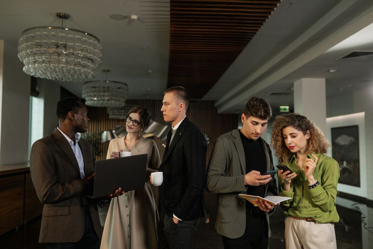 A group of colleagues in smart-casual clothing standing and networking indoors